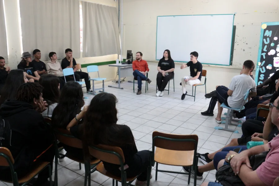 Jovens e professores sentados em uma sala de aula, participando do projeto 'Cambia' de cidadania ambiental levado pela UNESC a Criciúma.
