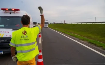Vagas de Verão: ViaCosteira contrata para praças de pedágio Funcionário da CCR ViaCosteira com colete refletivo amarelo, orientando o trânsito na BR-101, em contexto de vagas de emprego para a alta temporada.