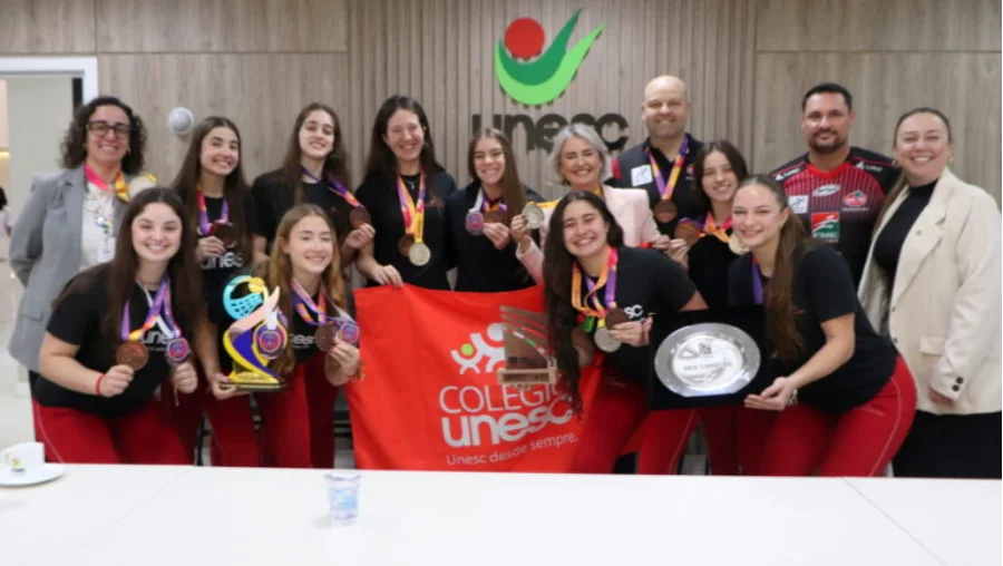 Jogadoras de vôlei de Criciúma celebrando com medalhas a classificação para a Superliga B, em evento na UNESC.