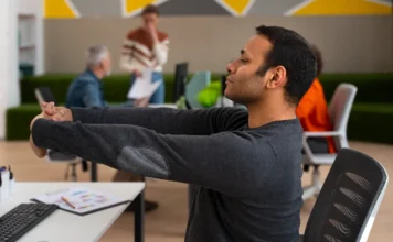 60% dos brasileiros negligenciam pausas no expediente Homem fazendo alongamento na cadeira do escritório e fechando os olhos para um breve descanso, ilustrando a negligência dos trabalhadores brasileiros em fazer pausas regulares durante o expediente, o que afeta a produtividade e a saúde mental.