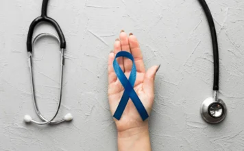 Araranguá terá mutirão de saúde em todo o município Mão segurando a fita azul, símbolo do Novembro Azul, ao lado de um estetoscópio, ilustrando o mutirão de saúde e a campanha de conscientização sobre o câncer de próstata e o cuidado integral do homem em Araranguá.