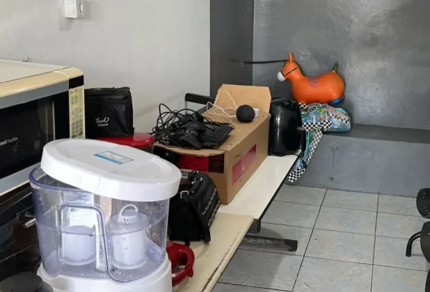 Filtro de água, micro-ondas, videogame e brinquedo (cavalinho inflável) recuperados e dispostos em uma mesa, após serem furtados e deixados no carro abandonado em Araranguá.