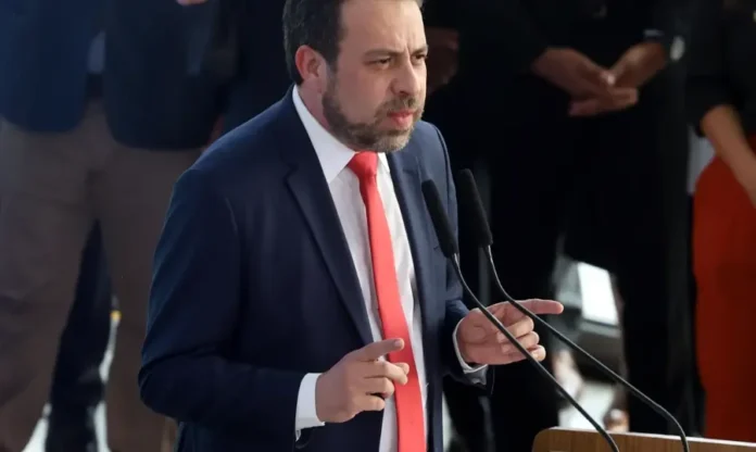 Boulos lança “Governo na Rua” para ouvir demandas sociais Ministro Guilherme Boulos, com terno azul e gravata vermelha, discursando em São Paulo no lançamento do projeto "Governo na Rua", que busca levar as demandas das periferias para a esfera federal.