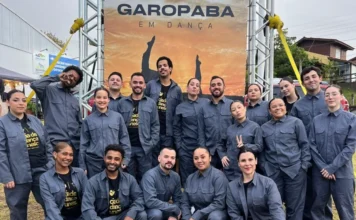 Cia de Dança Unesc conquista 1º lugar em Garopaba Grupo de bailarinos da Cia de Dança Unesc, vestindo uniformes cinzas, posando juntos em frente a um banner do evento "Garopaba em Dança".