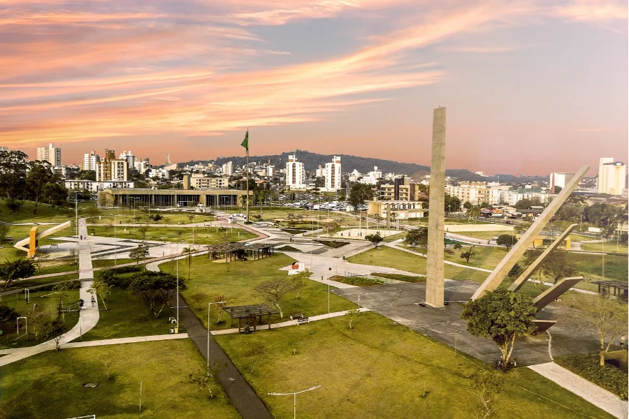 Criciúma Centenário altera serviços na Saúde e Educação Vista aérea do Paço Municipal Marcos Rovaris e do Parque da Prefeitura em Criciúma, com o obelisco em destaque, ilustrando o feriado do Centenário que altera os serviços municipais de Saúde e Educação.