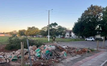 Demolição de portal gera debate sobre história em Sombrio Montanha de escombros do portal demolido no terreno do antigo Estádio Cairú, em Sombrio, com o campo de grama e casas ao fundo, ilustrando a controvérsia sobre o marco histórico da cidade.
