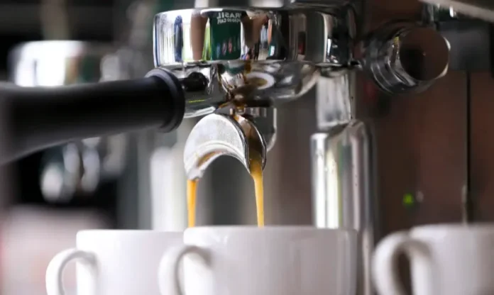 Estudo Café reduz em 39% risco de arritmia cardíaca Close-up na máquina de café expresso com a bebida sendo extraída em xícaras brancas, ilustrando o consumo diário de café que, segundo estudo de universidades nos EUA e Austrália, reduz em 39% o risco de arritmia cardíaca.