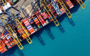 FIESC defende flexibilidade do Mercosul para acordos Visão aérea de um porto com guindastes e navio de contêineres carregado, ilustrando o comércio internacional e as movimentações de carga no Mercosul.