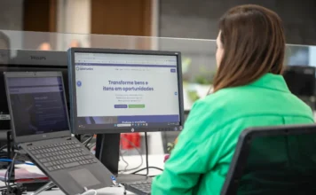 FIESC lança site que conecta indústria e doações Funcionária da FIESC de costas olhando para a tela que exibe o site do Programa Oportuniza da Federação.