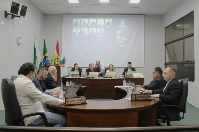 Forquilhinha Câmara estreia sistema eletrônico de votação Sessão na Câmara de Vereadores de Forquilhinha com vereadores reunidos à mesa e o telão ao fundo exibindo o placar do novo sistema eletrônico de votação, que visa modernizar os trabalhos do Legislativo.