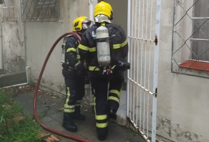 Fumaça em Correios mobiliza Bombeiros no centro de Meleiro Dois Bombeiros Militares com equipamentos de oxigênio inspecionando a porta dos fundos da agência dos Correios de Meleiro, após o acionamento de sistema de segurança que gerou fumaça no interior do prédio.