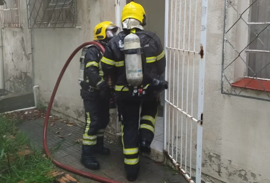 Fumaça em Correios mobiliza Bombeiros no centro de Meleiro Dois Bombeiros Militares com equipamentos de oxigênio inspecionando a porta dos fundos da agência dos Correios de Meleiro, após o acionamento de sistema de segurança que gerou fumaça no interior do prédio.