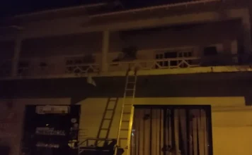 Incêndio atinge prédio em Jacinto Machado Prédio de dois andares atingido por incêndio em Jacinto Machado, com uma escada de bombeiros apoiada na varanda para o acesso ao piso superior.