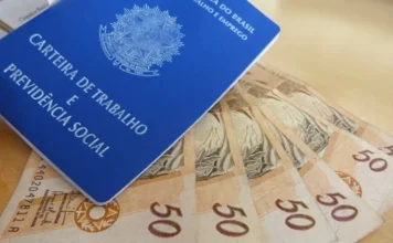 Indústria de SC fecha 2,9 mil vagas, pior resultado desde 2020 Carteira de Trabalho e Previdência Social (CTPS) azul sobre várias notas de R$ 50, simbolizando emprego formal e remuneração.