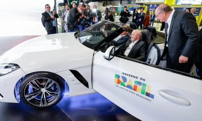 Lula celebra retirada de tarifas dos EUA como “vitória do diálogo” Lula em carro branco com a logo do Governo do Brasil, na abertura do Salão Internacional do Automóvel.