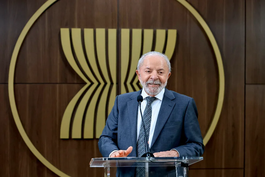 Presidente Lula (imagem ilustrativa), sorrindo e discursando em um púlpito, representando o debate diplomático sobre a presença de navios de guerra dos EUA com a Celac e a União Europeia.
