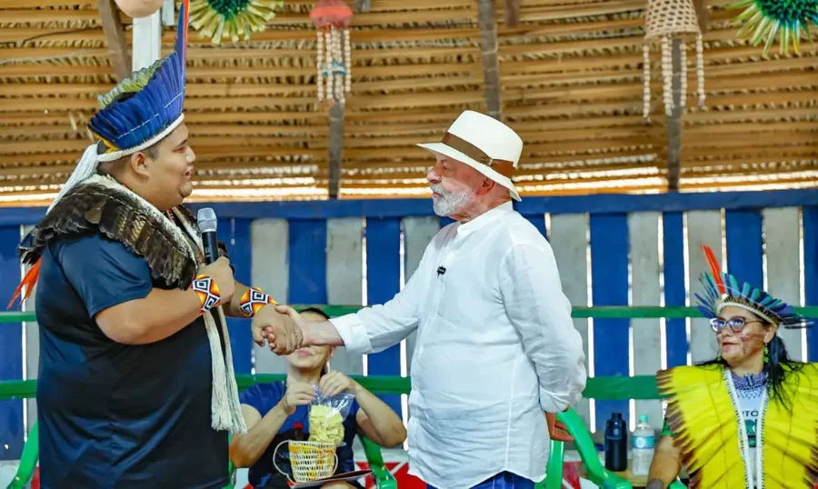 Presidente Lula (de chapéu branco) cumprimenta um líder da comunidade indígena ou ribeirinha durante sua visita à Amazônia, debatendo bioeconomia e sustentabilidade antes da COP30.