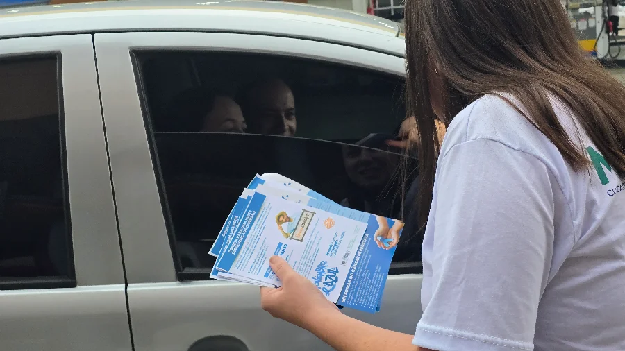 Morro da Fumaça inicia campanha Novembro Azul com blitz Profissional de saúde entregando folhetos informativos para motoristas e passageiros de carro em uma blitz, marcando o início da campanha Novembro Azul em Morro da Fumaça.