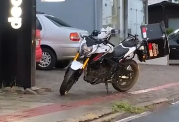 Motociclista sofre mal súbito e morre no centro de Sombrio Motocicleta branca e preta deitada na calçada no centro de Sombrio, após mal súbito do condutor.