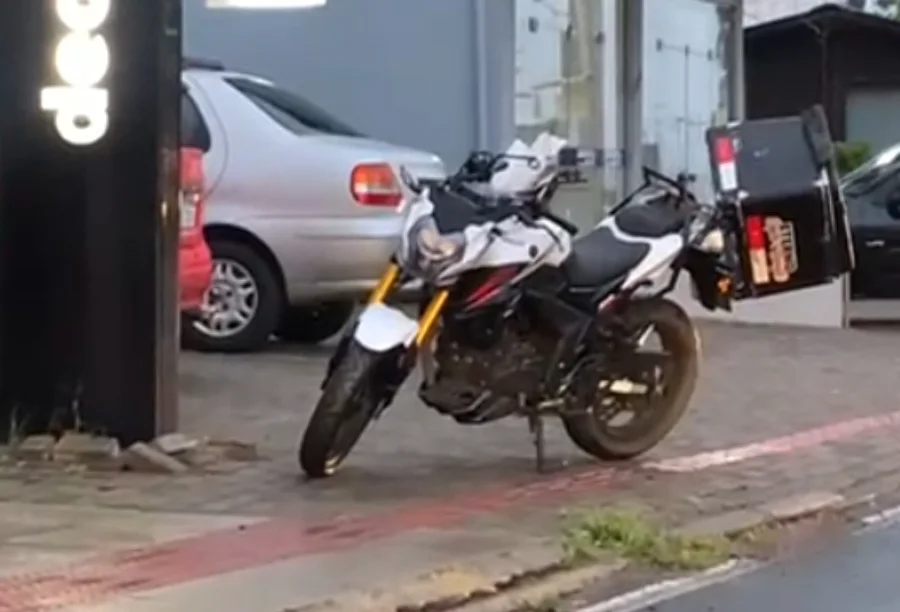 Motocicleta branca e preta deitada na calçada no centro de Sombrio, após mal súbito do condutor.
