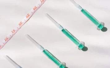 Mounjaro e Nutrição – o que sustenta o resultado! Quatro seringas pré-preenchidas contendo medicamento de cor verde-água (alusão ao Mounjaro/tirzepatida) dispostas diagonalmente ao lado de uma fita métrica.