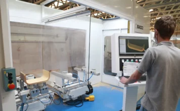 SC tem 2º maior crescimento do país na atividade econômica Operário em uma fábrica controlando uma máquina industrial automatizada que está processando peças de madeira, ilustrando a produção industrial de Santa Catarina.