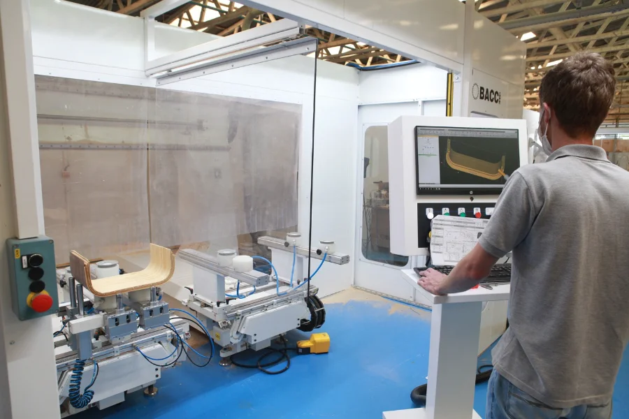 SC tem 2º maior crescimento do país na atividade econômica Operário em uma fábrica controlando uma máquina industrial automatizada que está processando peças de madeira, ilustrando a produção industrial de Santa Catarina.