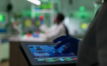 SENAI/SC avança na biotecnologia com estudo pioneiro Cientista utilizando um tablet em laboratório para analisar uma visualização de estruturas celulares, representando o estudo pioneiro do SENAI SC e seus parceiros (Duas Rodas/Embrapii) no desenvolvimento de um meio de cultura celular sustentável com o uso de biotecnologia e Inteligência Artificial.