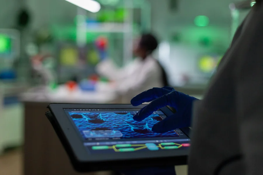 Cientista utilizando um tablet em laboratório para analisar uma visualização de estruturas celulares, representando o estudo pioneiro do SENAI SC e seus parceiros (Duas Rodas/Embrapii) no desenvolvimento de um meio de cultura celular sustentável com o uso de biotecnologia e Inteligência Artificial.