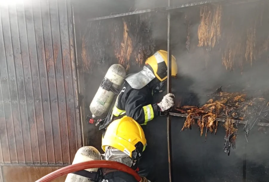 São João do Sul Incêndio atinge estufa de fumo na zona rural Bombeiros com capacetes amarelos e equipamentos de oxigênio combatendo o incêndio dentro de uma estufa de fumo na zona rural de São João do Sul.