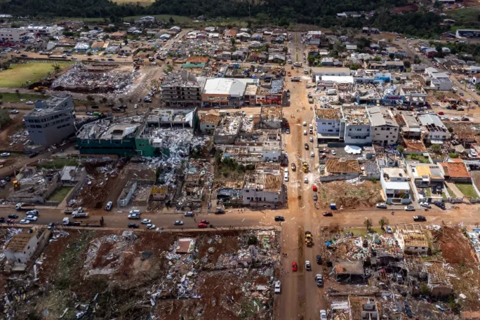 Tornado Reconstrução de Rio Bonito do Iguaçu precisa de ajuda Vista aérea do centro de Rio Bonito do Iguaçu (PR) após ser atingida por um tornado, mostrando casas e edifícios comerciais totalmente destruídos e escombros espalhados pelas ruas, em meio ao apelo urgente por doações para a reconstrução.
