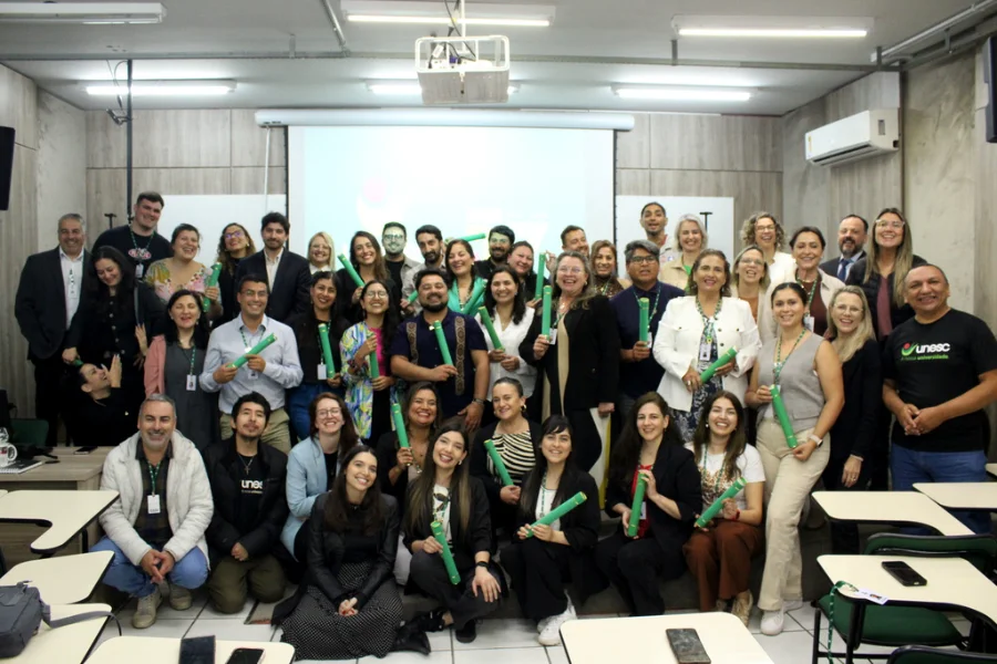 Unesc encerra imersão de chilenos no SUS brasileiro Grande grupo de 26 profissionais de saúde chilenos, ao lado de professores da UNESC, posando com certificados após a imersão de dez dias no funcionamento do SUS brasileiro.