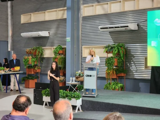 Apresentação em palco de evento universitário, com palestrantes em frente a uma tela que exibe o lançamento dos novos cursos de Fonoaudiologia e Terapia Ocupacional.