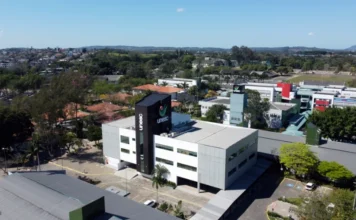 Unesc reafirma papel central no Centenário de Criciúma Vista aérea do moderno campus da UNESC em Criciúma, destacando o prédio principal com o logo vertical, simbolizando o papel da universidade no desenvolvimento da cidade em seu Centenário.