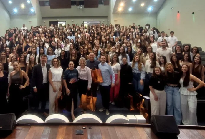 Unesc sedia Jornada de Biomedicina com recorde de inscrições Auditório lotado com mais de 300 acadêmicos do curso de Biomedicina (UNESC), e a reitora Gisele Coelho Lopes e equipe organizadora no palco, celebrando o recorde de inscrições da 11ª Jornada Acadêmica em Criciúma.