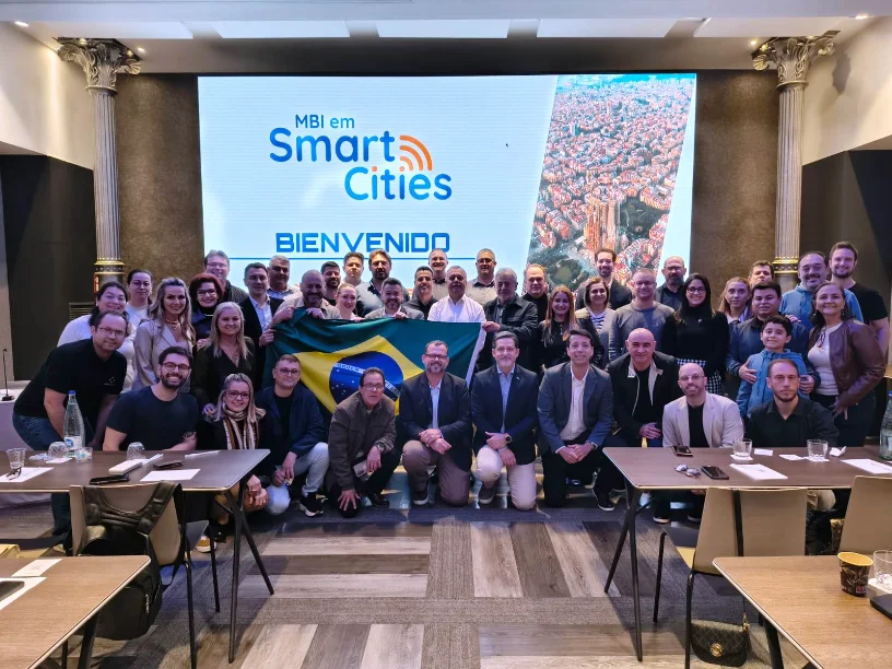 Grande grupo de prefeitos, secretários e alunos do MBI em Smart Cities do UniSENAI/FIESC, segurando a bandeira do Brasil, no encerramento da missão internacional em Barcelona (Espanha) para estudar tecnologias de cidades inteligentes.