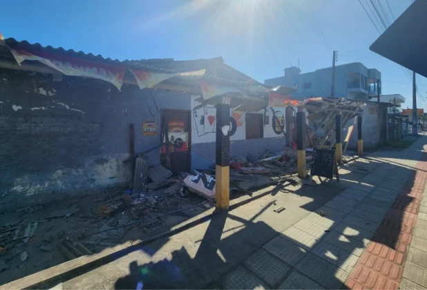 Fachada de um bar ou comércio com telhado e estrutura de madeira destruídos e caída na calçada, mostrando os estragos causados pelo vendaval em Balneário Gaivota ou Sombrio.