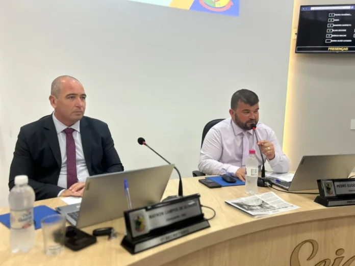 Vereadores de Arroio do Silva pedem reorganização de fiação Dois vereadores sentados em mesa de sessão na Câmara de Balneário Arroio do Silva, com um deles falando ao microfone.