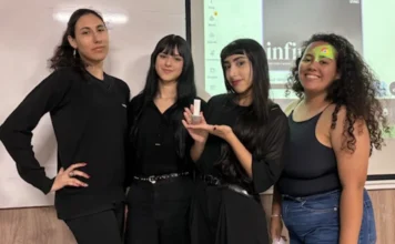 Acadêmicos de Design da Unesc criam projetos para a Dexco Quatro estudantes de Design da Unesc sorriem em frente a um telão de apresentação. Uma das alunas segura um protótipo físico de metal sanitário desenvolvido para a Deca. O grupo veste roupas pretas e azuis, e ao fundo aparece o logotipo do curso e parte da apresentação digital.