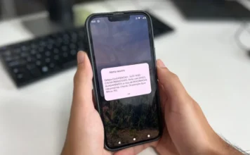 Alerta de tempestade chega a celulares sem cadastro em Sombrio Pessoa segurando um celular que exibe um Alerta Severo da Defesa Civil sobre chuva persistente, forte com raios e risco de alagamentos.