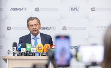 Alesc economiza e devolve R$ 403 milhões ao Governo de SC O presidente da Assembleia Legislativa de Santa Catarina, deputado Julio Garcia, fala em um púlpito cercado por microfones de diversas emissoras de rádio e TV. Ao fundo, um painel branco exibe as logomarcas da Alesc, Agência AL e TVAL. Em primeiro plano, o desfoque de um celular registrando a coletiva de imprensa.