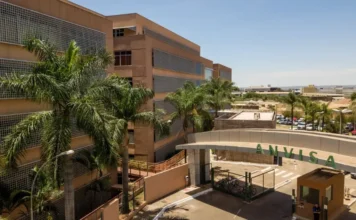 Anvisa manda recolher tônico capilar que simula efeito de Minoxidil Fachada da sede da ANVISA em Brasília, mostrando um prédio marrom de vários andares, palmeiras e a entrada principal com o nome da agência em letras verdes.