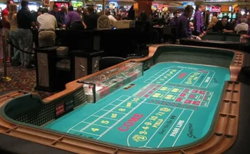 Apostas online custam R$ 38,8 bilhões ao Brasil por ano Mesa de jogo de craps (dados) em um cassino lotado, ilustrando jogos de azar e apostas.