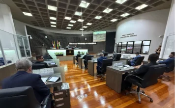 Araranguá aprova Cabines TEA para conforto sensorial em eventos Plenário da Câmara de Vereadores de Araranguá com vereadores sentados em plenário de piso de madeira, durante sessão.