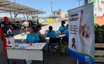 Arroio do Silva intensifica testes rápidos no Dezembro Vermelho Equipe de saúde vestida de azul realizando campanha de testagem rápida de HIV/ISTs em uma tenda em frente a um supermercado em Balneário Arroio do Silva.