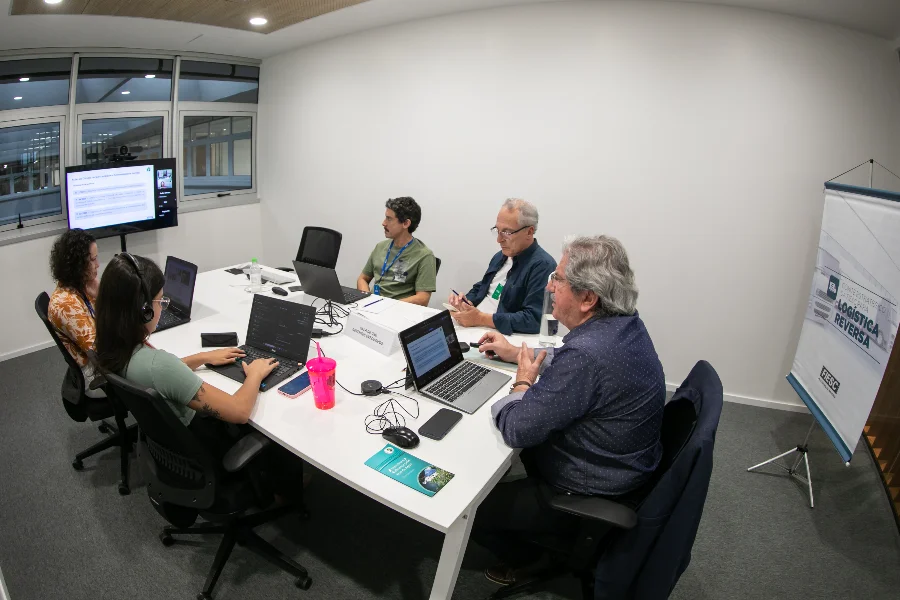 COP30 cria Coalizão Aberta para Mercados de Carbono Reunião em sala de escritório com cinco pessoas sentadas em torno de uma mesa, com notebooks abertos, discutindo a Coalizão Aberta para Mercados de Carbono.