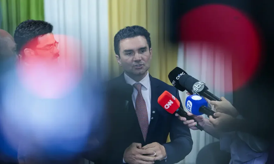 Celso Sabino deixa Ministério do Turismo União indica sucessor O ministro do Turismo, Celso Sabino, em um pronunciamento oficial. Ele veste um terno escuro, camisa branca e gravata em tom sóbrio. O ministro está posicionado de frente, com uma expressão serena, à frente de um fundo neutro e desfocado que sugere um ambiente de gabinete governamental.