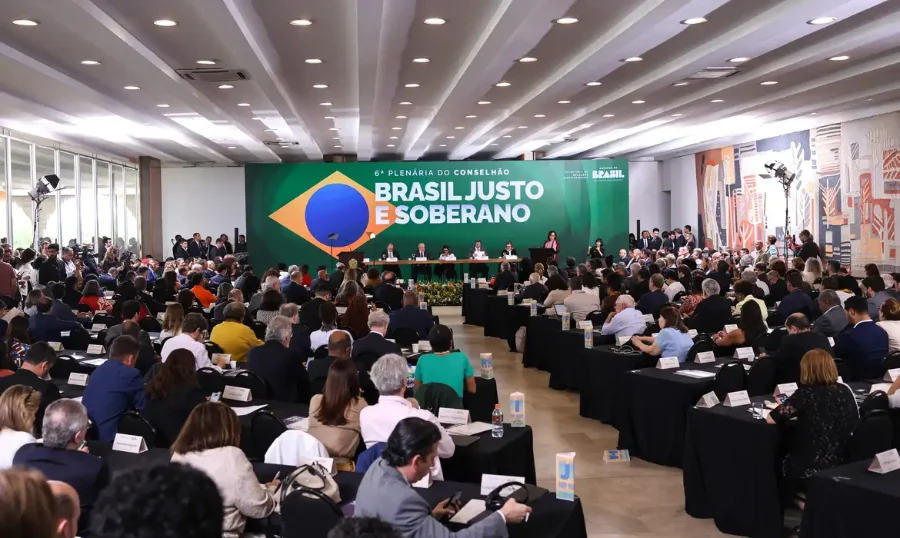 Plenária do Conselhão (CDESS) no Palácio Itamaraty, com centenas de representantes do governo, sociedade civil e empresariado, em frente a um grande painel com a bandeira do Brasil.