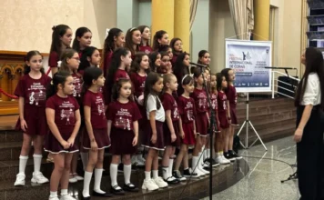 Criciúma abre 25º Festival de Corais com grupos do Uruguai Coral infantil feminino canta em degraus na Catedral São José, com uma maestrina ao lado, durante a abertura do Festival Internacional de Corais.