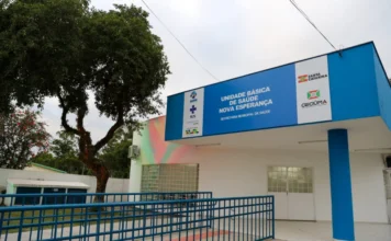 Criciúma entrega reforma da UBS Vila Nova Esperança Fachada da Unidade Básica de Saúde do bairro Vila Nova Esperança em Criciúma. O prédio é branco com uma platibanda azul onde se lê "Unidade Básica de Saúde Vila Nova Esperança". Há uma rampa de acesso com corrimão azul à esquerda e uma árvore de grande porte ao lado da estrutura.